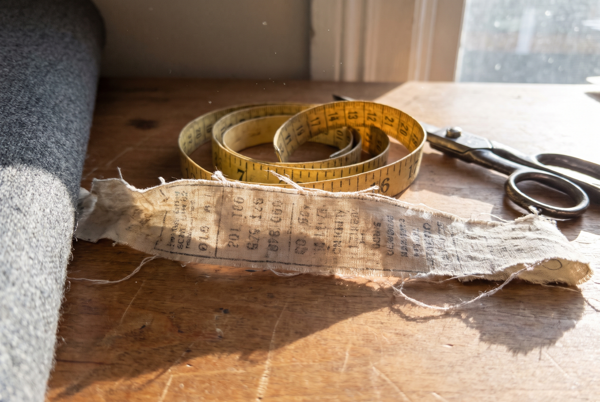 An old fabric content strip on the cutting table, next to a tape and shears.