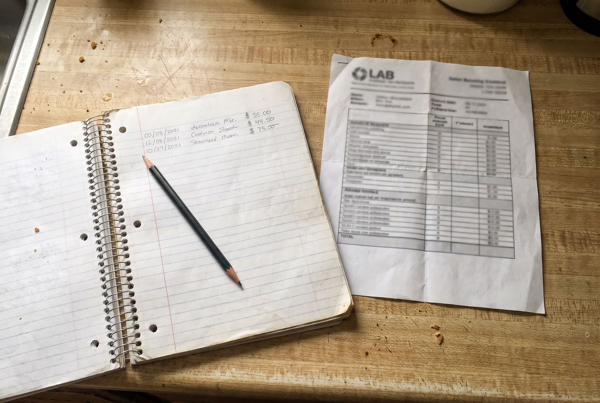 The notebook with dates and prices, and the lab sheet beside it.